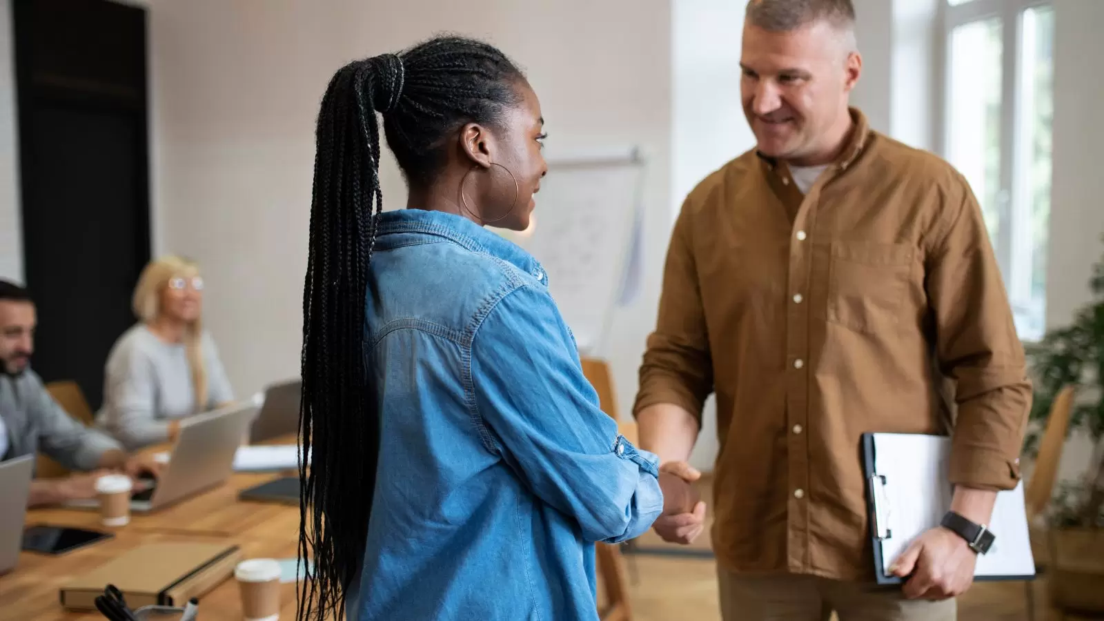 Mulher negra apertando mão de chefe branco
