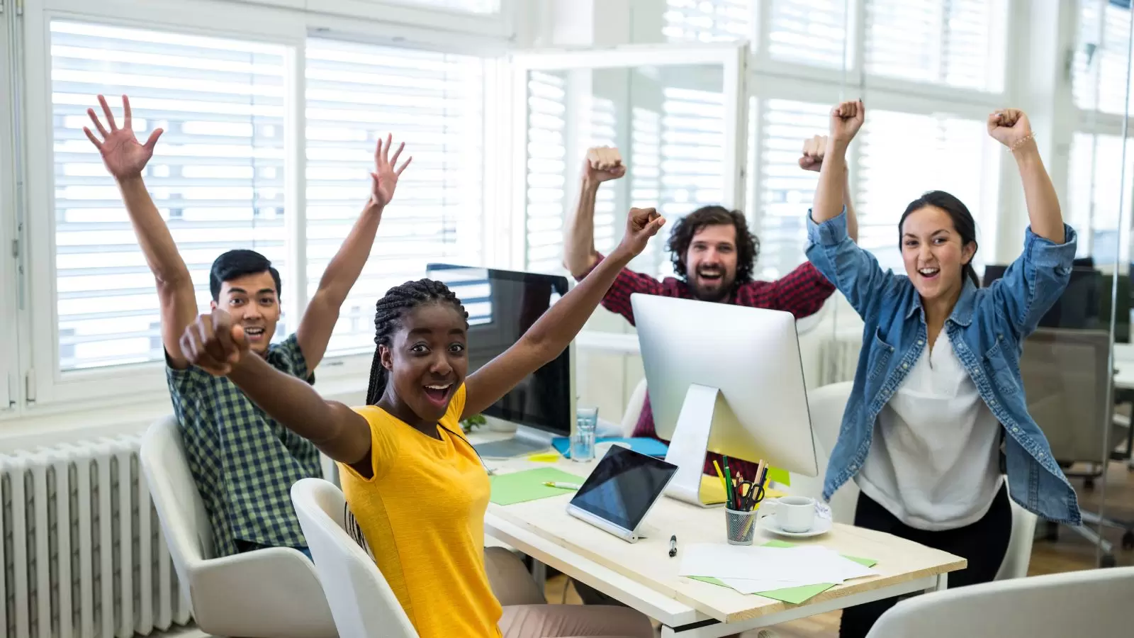 Grupo de colegas no trabalho de mãos levantadas e feliz