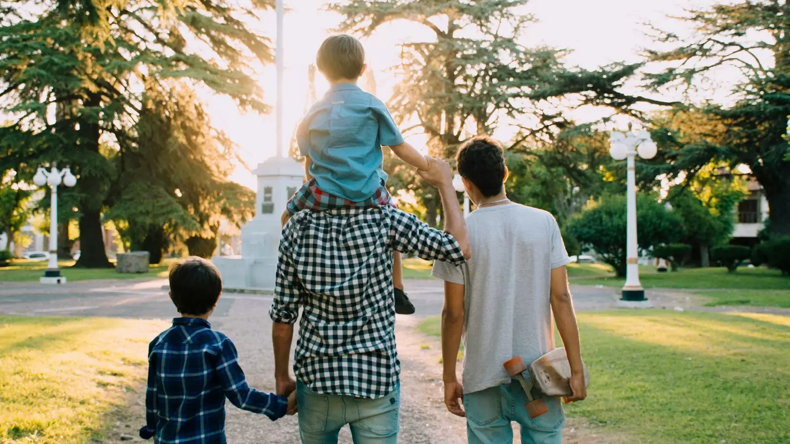 Homem com filhos ao lado, todos de costa
