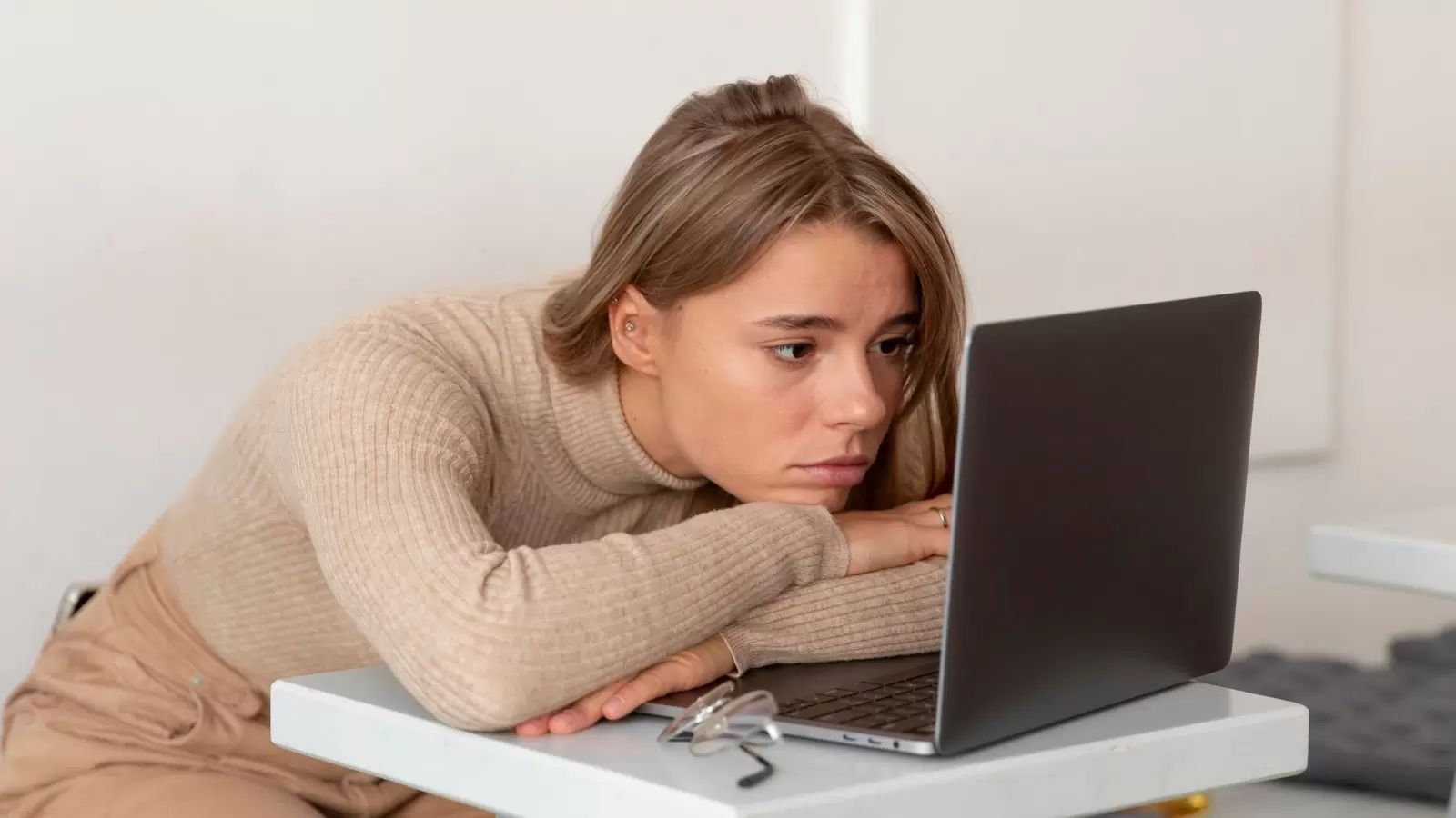 Jovem com semblante triste olhando para o notebook