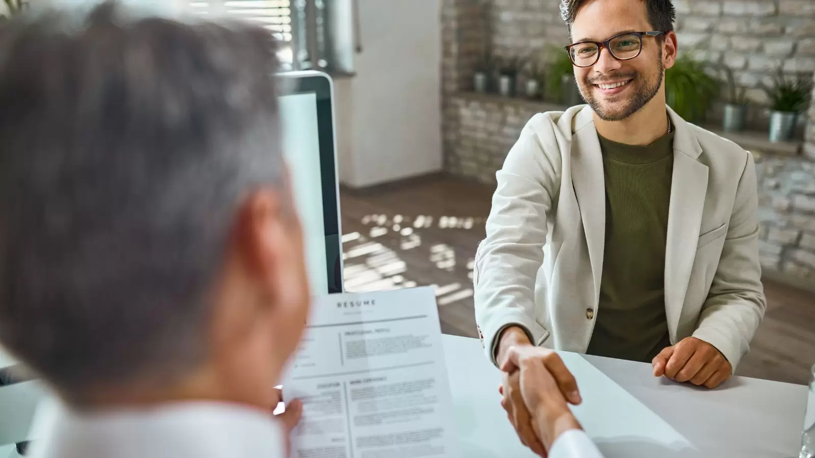 Jovem apertando mão de gestor em entrevista de emprego