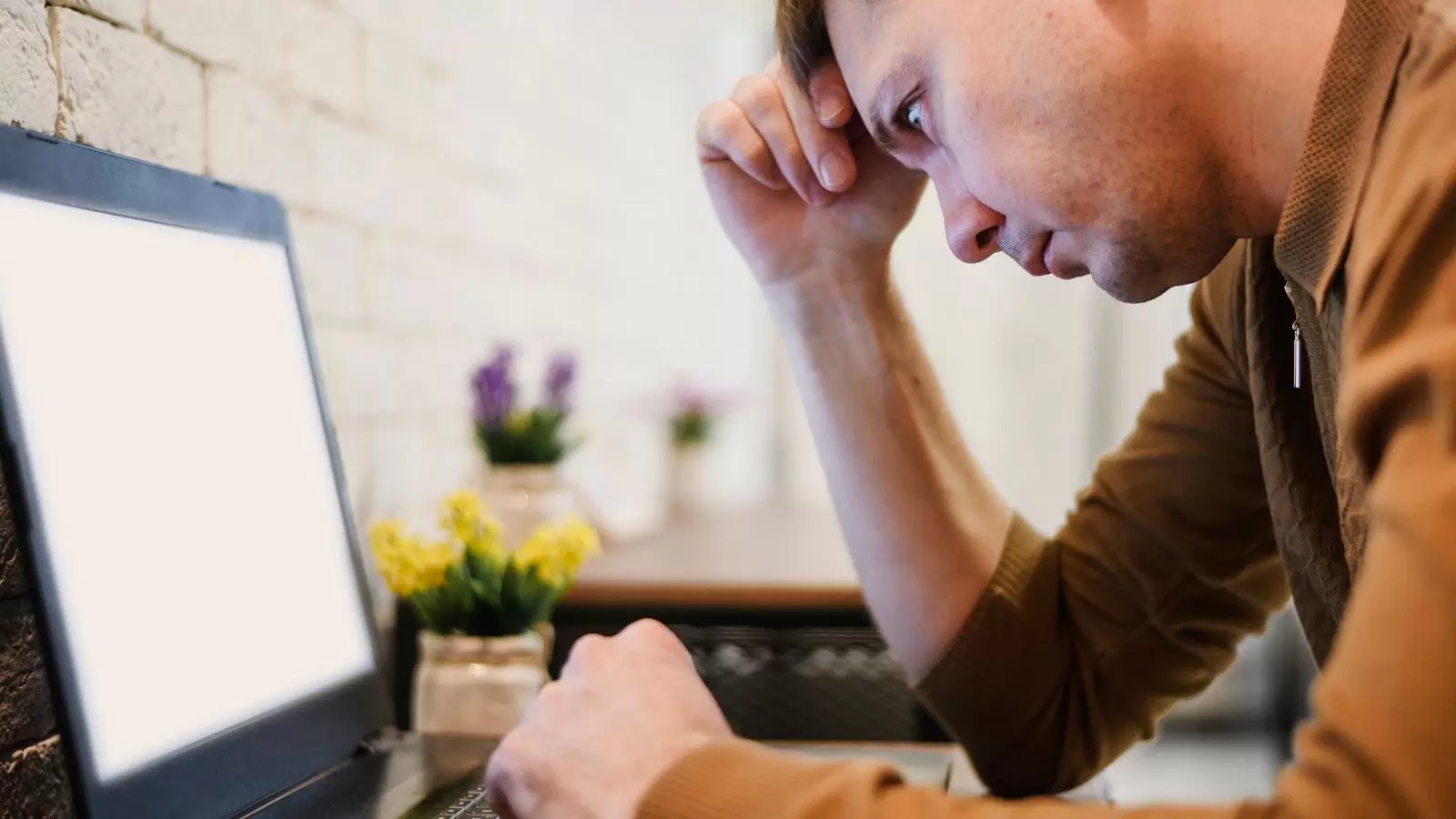 Pessoa mexendo em computador com semblante triste