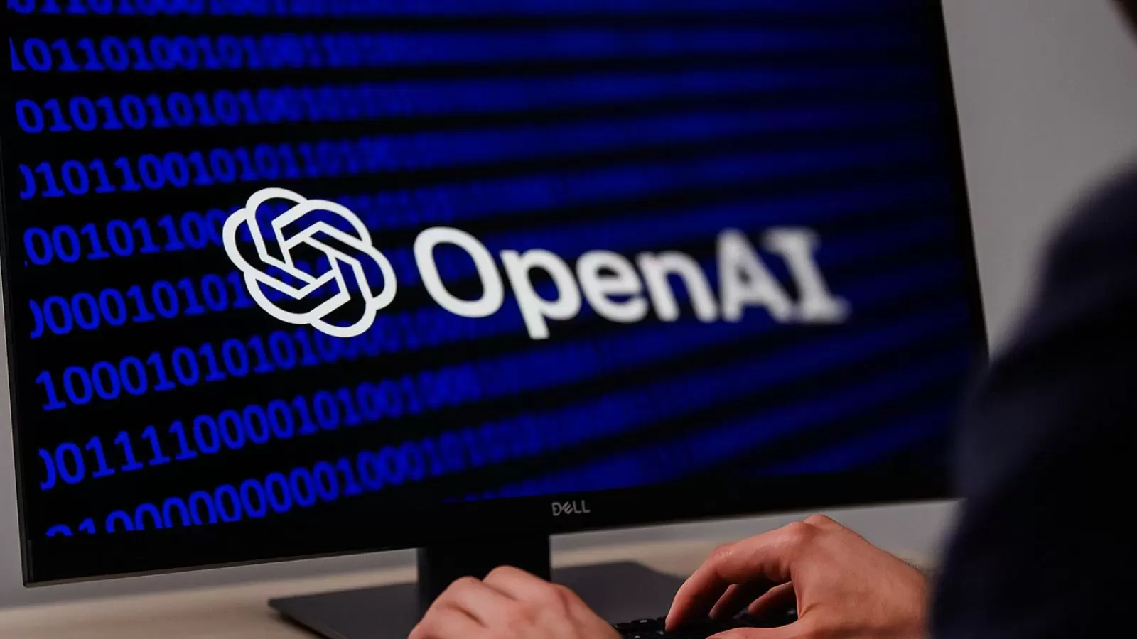 Pessoa mexendo no computador com símbolo da OpenAI
