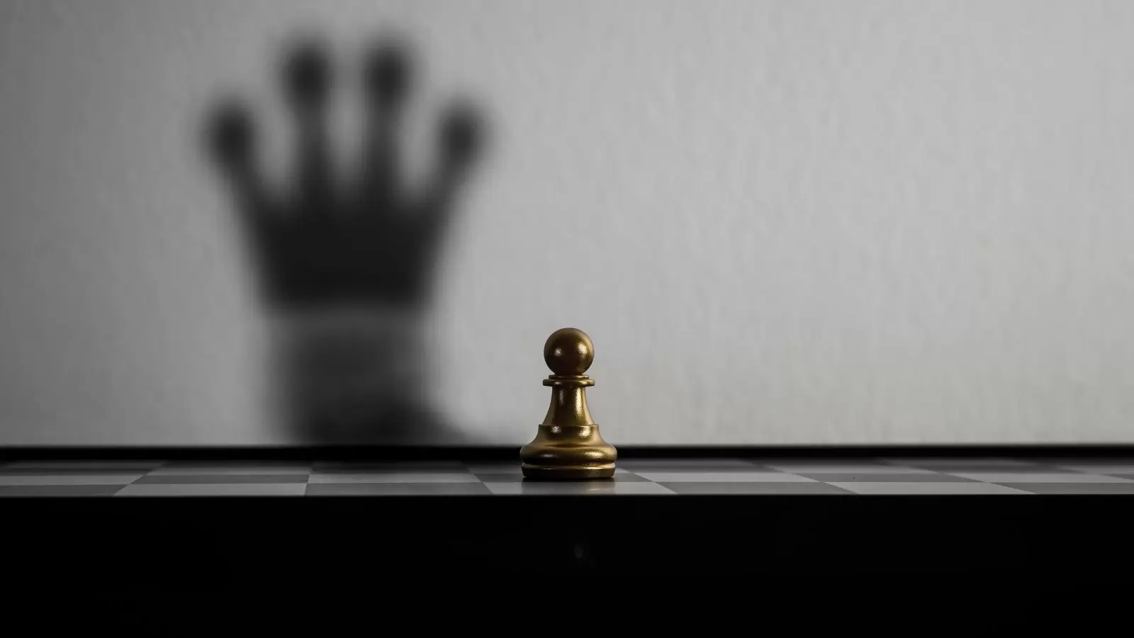 Peão de xadrez olhando sombra de rainha ao fundo