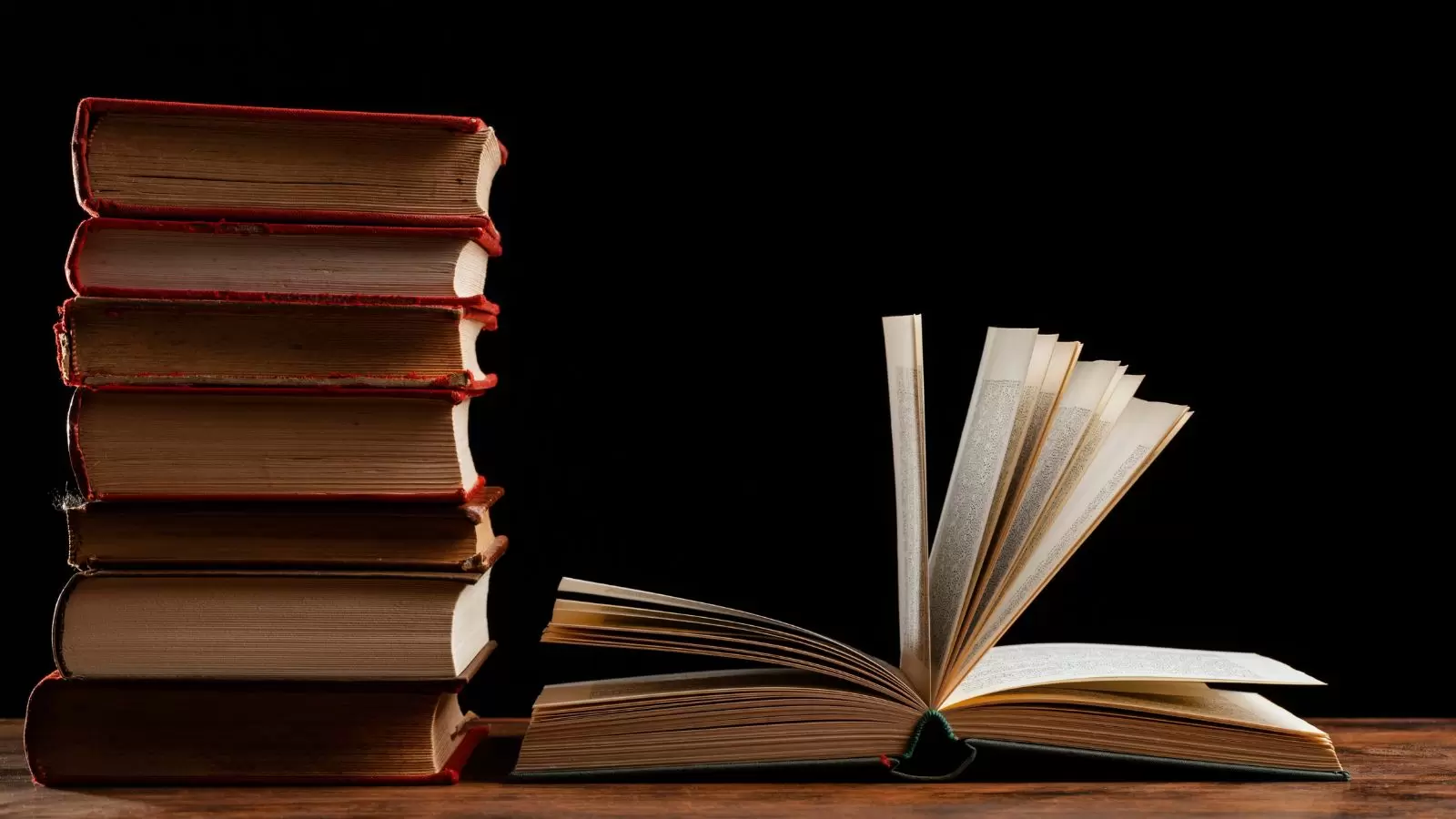 Pilha de livros e um aberto em fundo preto