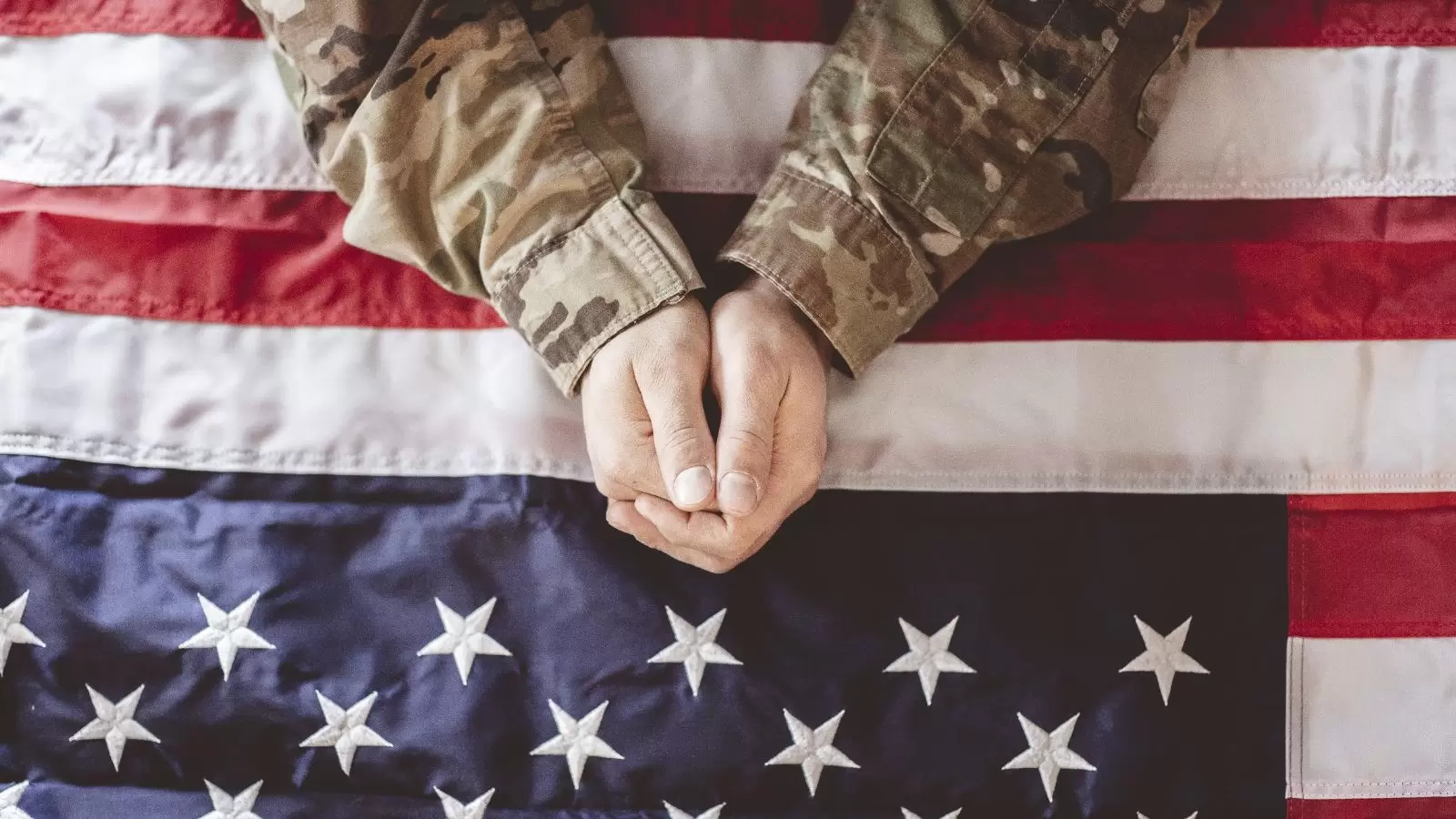 Mão de soldado em cima de bandeira dos EUA