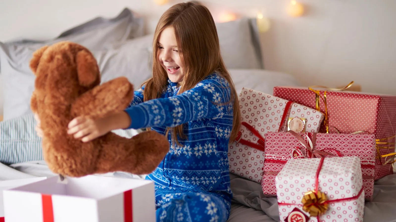Criança recebendo urso em caixa de presente