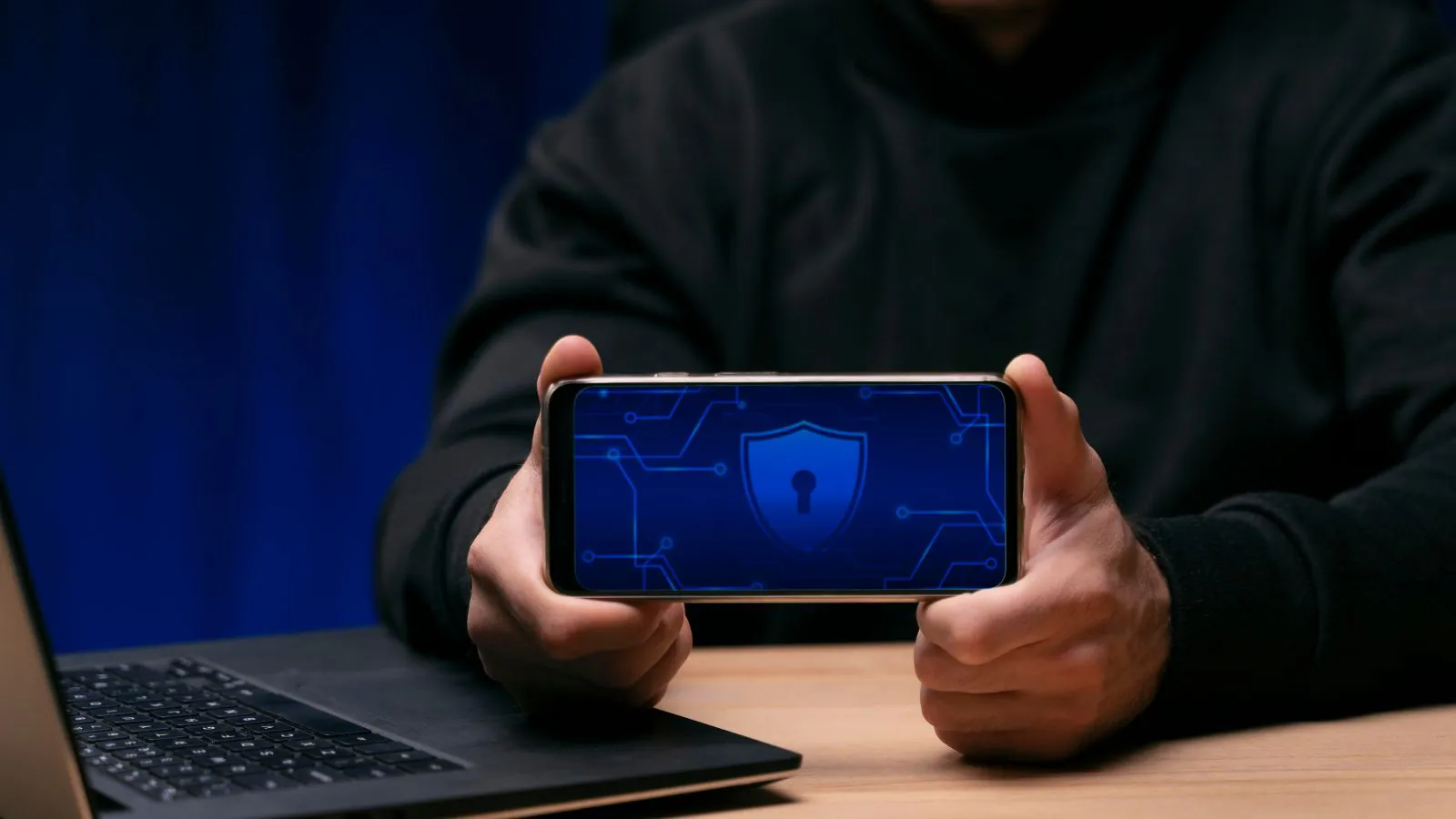 Pessoa de capuz segurando celular