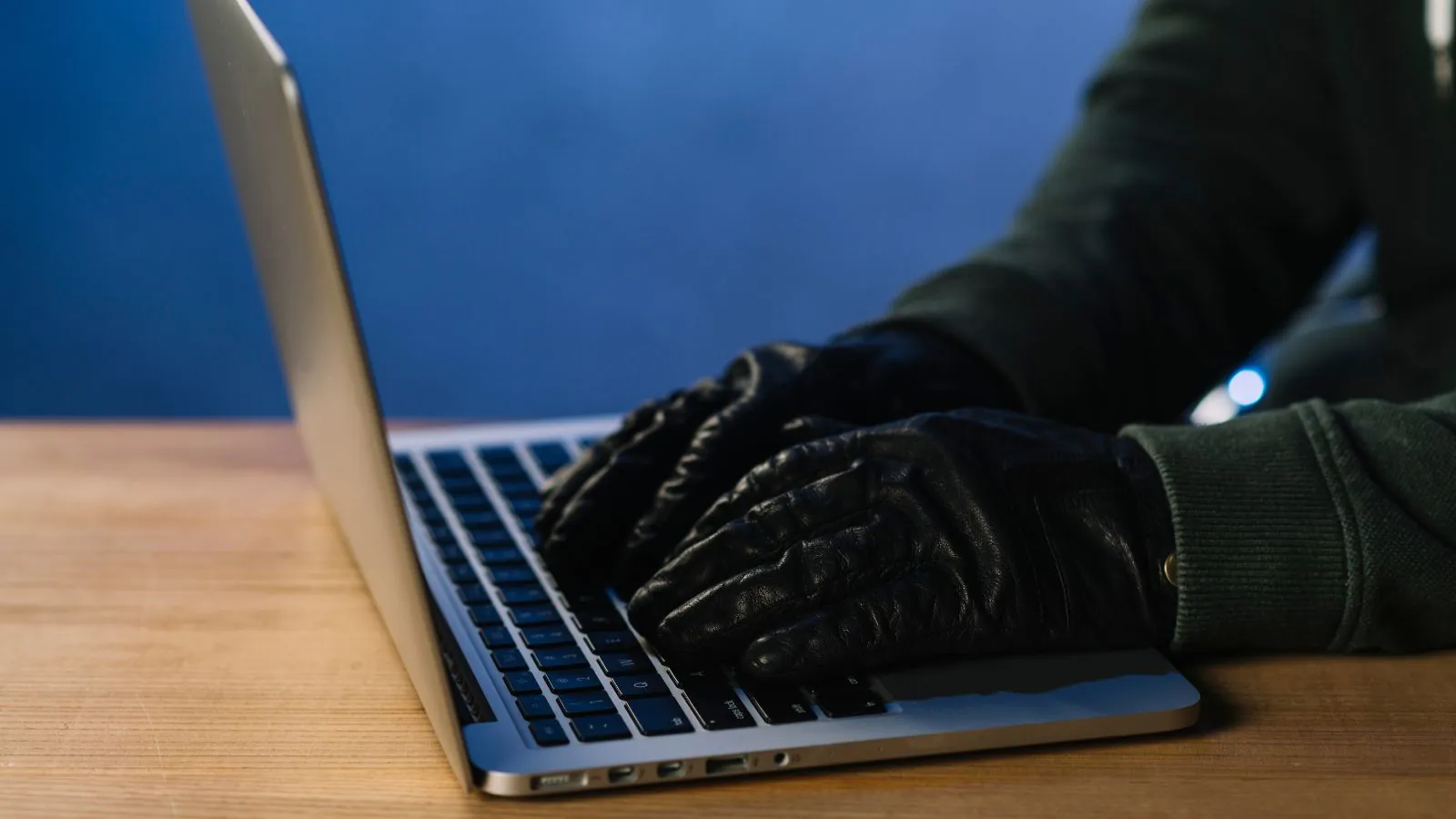 Mãos com luva preta mexendo em um notebook