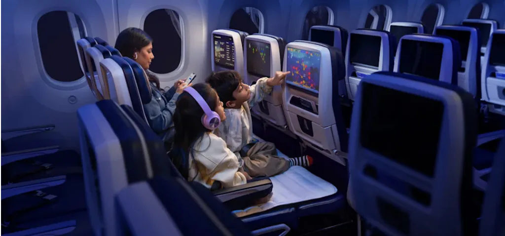 (mulher e duas crian&ccedil;as dentro de aeronave, uma delas usando fone e a outra brincando na tela)