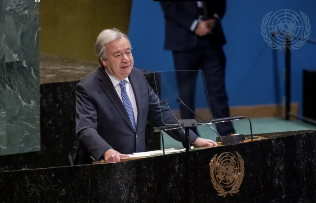 Homem de terno, Ant&oacute;nio Guterres, secret&aacute;rio-geral da ONU, fala em um p&uacute;lpito na Assembleia Geral da ONU, com o emblema das Na&ccedil;&otilde;es Unidas vis&iacute;vel no painel e ao fundo. A cena mostra um discurso oficial em ambiente diplom&aacute;tico.