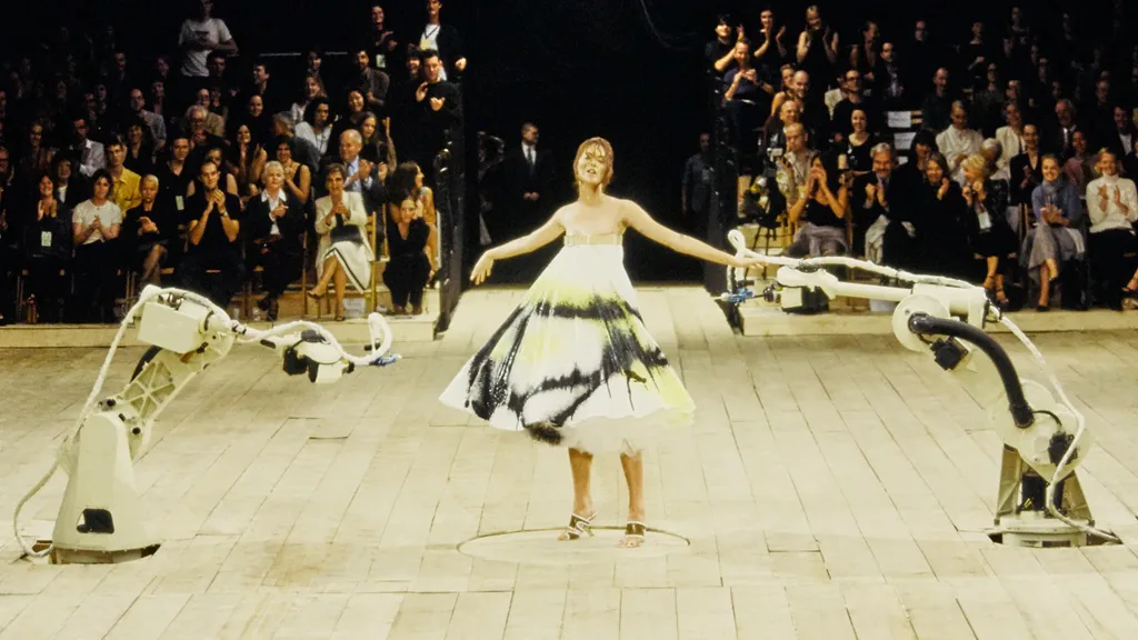 bra&ccedil;os mec&acirc;nicos espalham tinta em vestido branco em desfile da cole&ccedil;&atilde;o de Alexander McQuenn em 1999