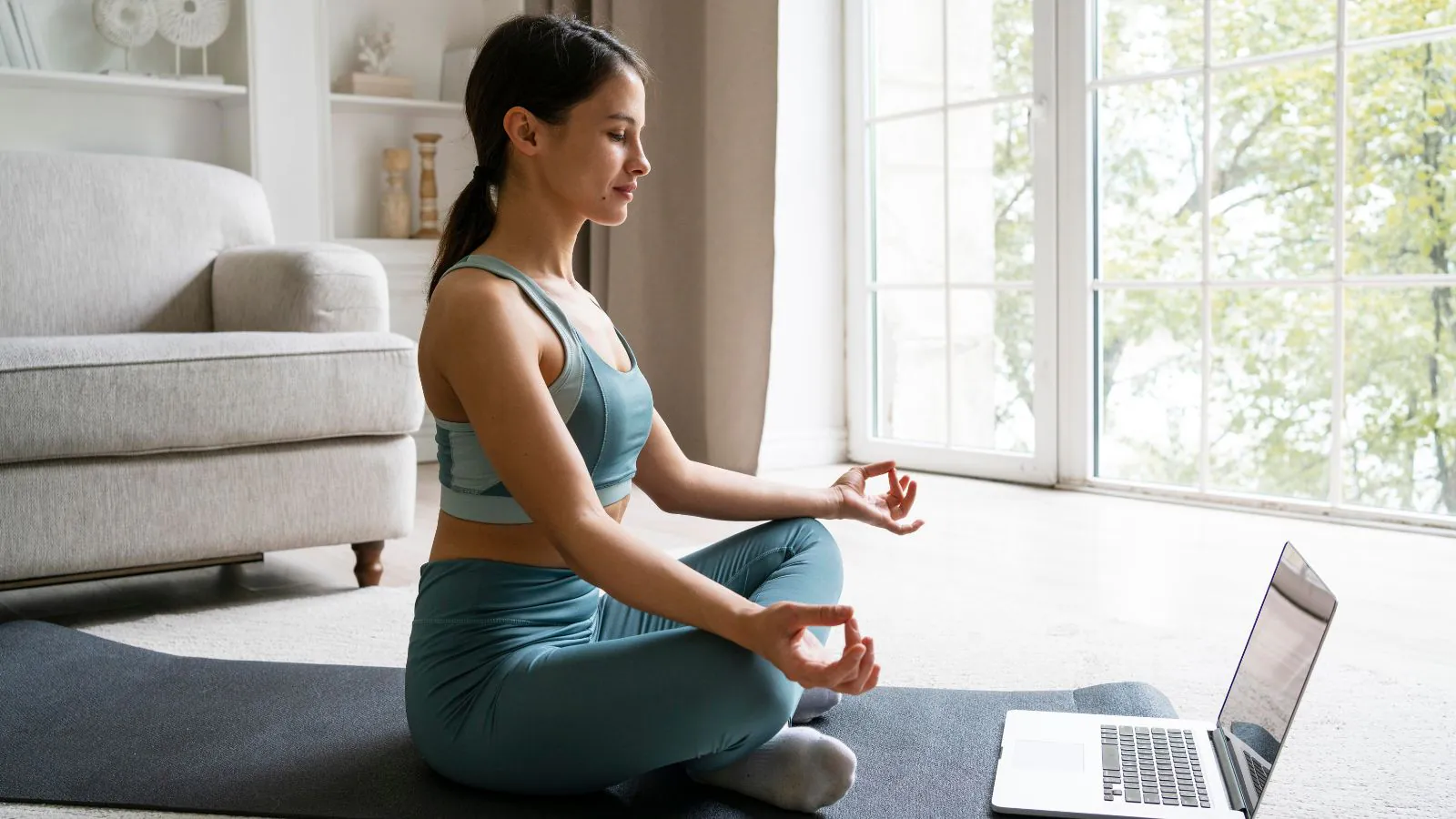 Mulher meditando em rente a um notebook.
