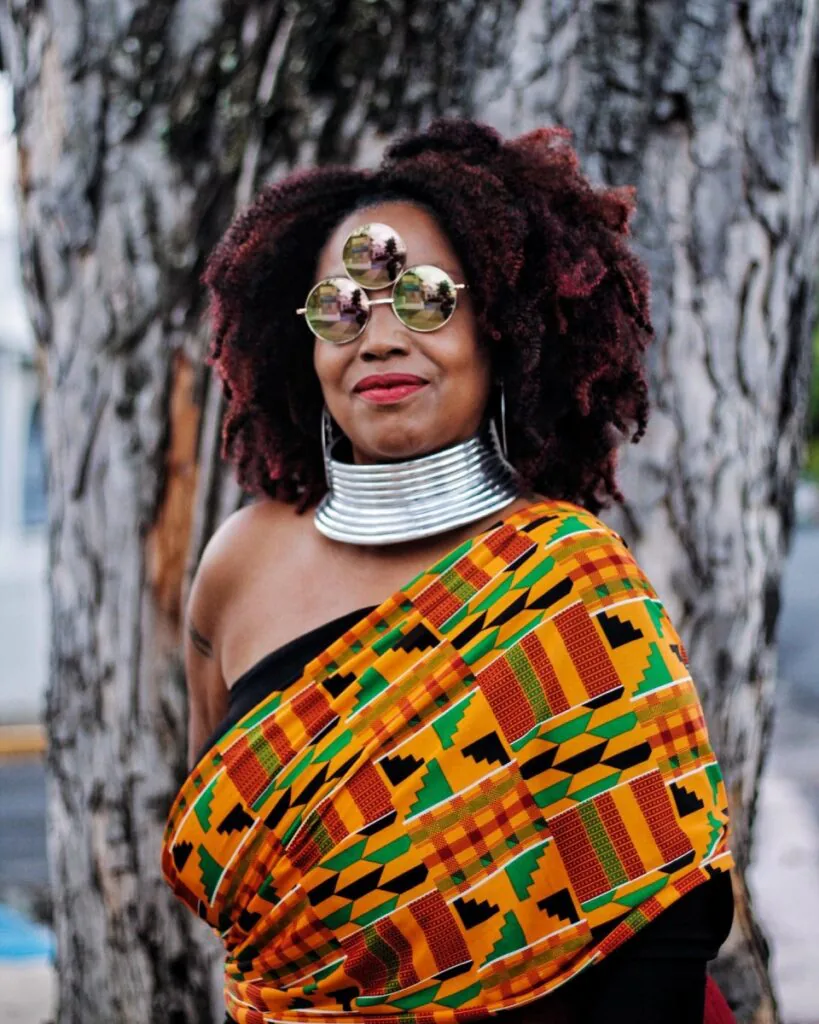 Retrato da escritora porto-riquenha Yolanda Arroyo Pizarro usando óculos de lentes espelhadas e tecido estampado