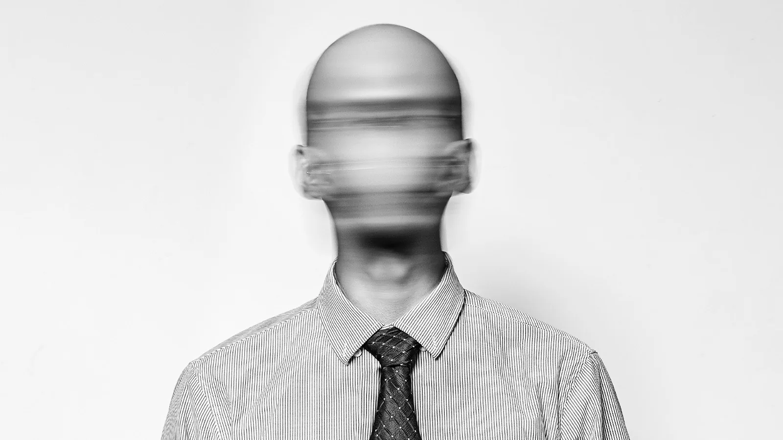 Homem de terno com o rosto borrado representa perda de identidade no trabalho