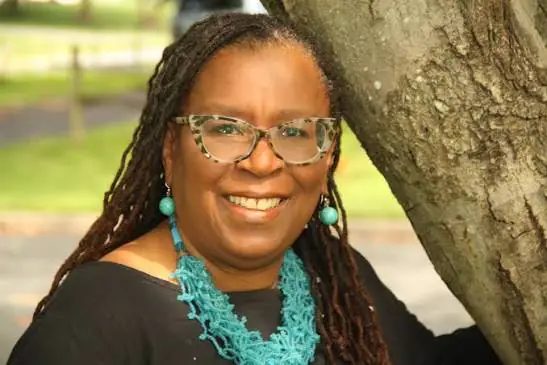 Retrato da futurista jamaicana Claire A. Nelson sorrindo ao lado de uma árvore