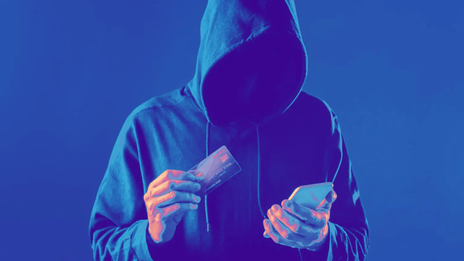 Homem de capuz segurando celular e cartão em fundo preto
