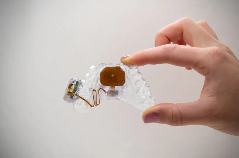 M&atilde;o segura o pequeno MouthPad transparente entre os dedos.