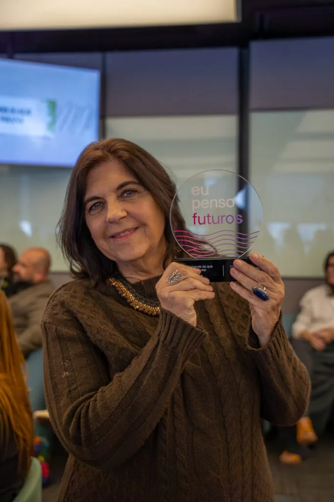 Rosa Alegria sorri enquanto segura um troféu com a frase “eu penso futuros”.