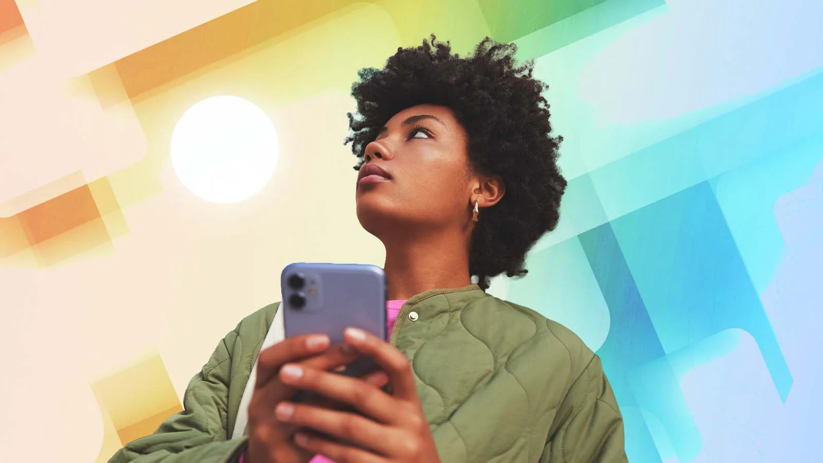 Mulher segura o celular e desvia o olhar da tela diante de um fundo colorido