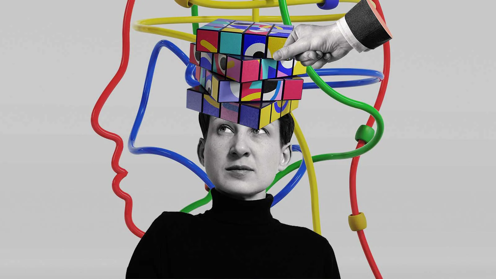 Pessoa com um cubo colorido sobre a cabeça enquanto uma mão reorganiza uma das peças