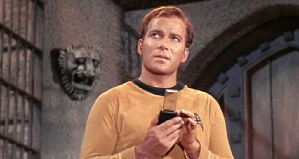 Capit&atilde;o Kirk segura um comunicador port&aacute;til em cena de Star Trek