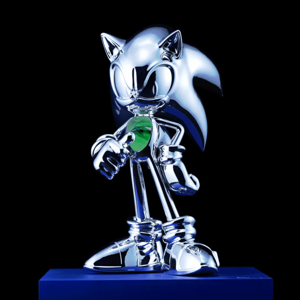 Figura colecionável cromada do Sonic, com uma Esmeralda do Caos verde no centro do peito, exibida sobre uma base azul.